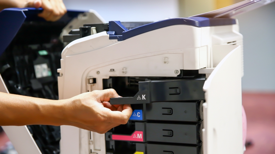 Technician hand open cover photocopier or photocopy to fix paper jam and replace ink cartridges for scanning fax or copy document in office workplace.